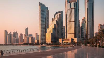 Al Maryah Island, Abu Dhabi at golden hour with modern glass-and-steel ADGM office towers and a wide pedestrian promenade