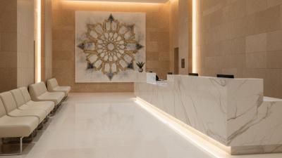 Modern hospital reception interior with polished marble desk, empty waiting chairs, and warm uplighting