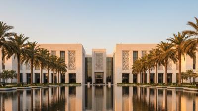 Modern Abu Dhabi government building exterior at golden hour with a contemporary white-stone facade and a wide reflecting pool