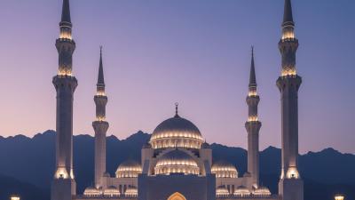 Sheikh Zayed Mosque Fujairah at blue hour: a large white-and-beige stone mosque with six tall slender minarets and multiple domes, subtly uplit against a deep twilight indigo sky with the silhouette of the Hajar Mountains in the distance