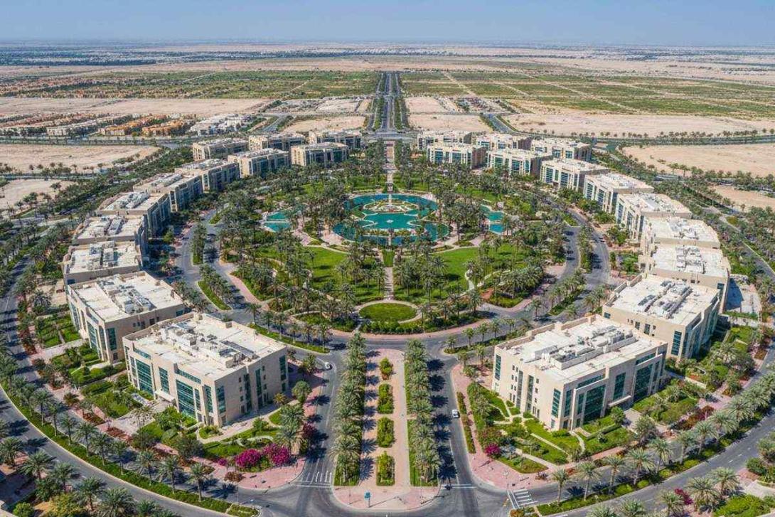 Aerial midday view of Dubai Silicon Oasis with low-rise tech-park buildings, tree-lined boulevards, and palm-lined parks