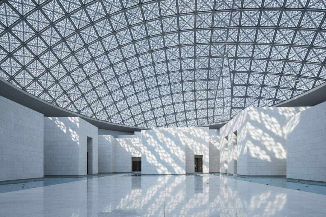 Interior of Louvre Abu Dhabi: dramatic 'rain of light' patterns filter through the geodesic silver dome, casting hundreds of overlapping star-shaped light shapes across pristine white limestone walls and a polished stone floor