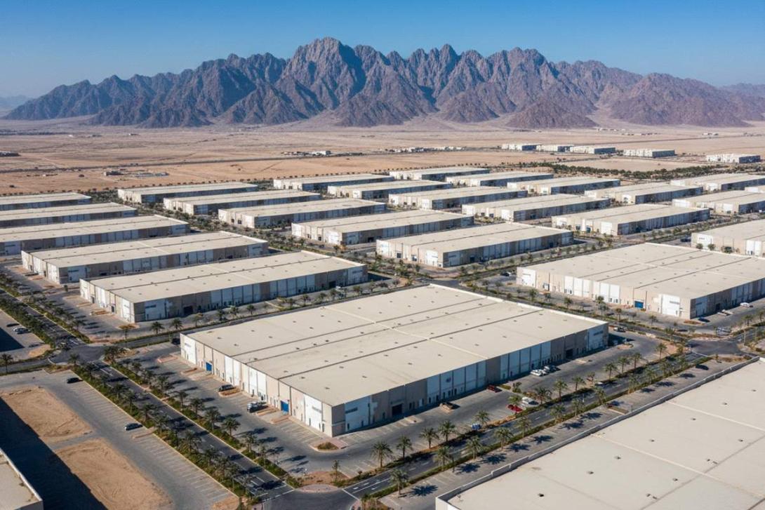Aerial view of an industrial business park in Ras Al Khaimah with low-rise warehouses and the Hajar Mountains in the background